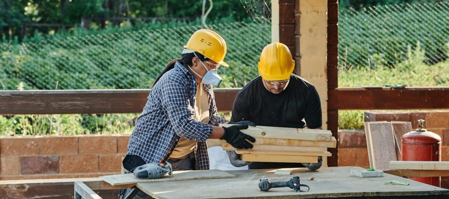 A Man in Black Shirt Carrying Wooden Planks